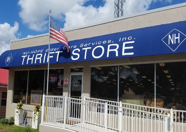 nu-hope cutting large white ribbon in front of thrift store